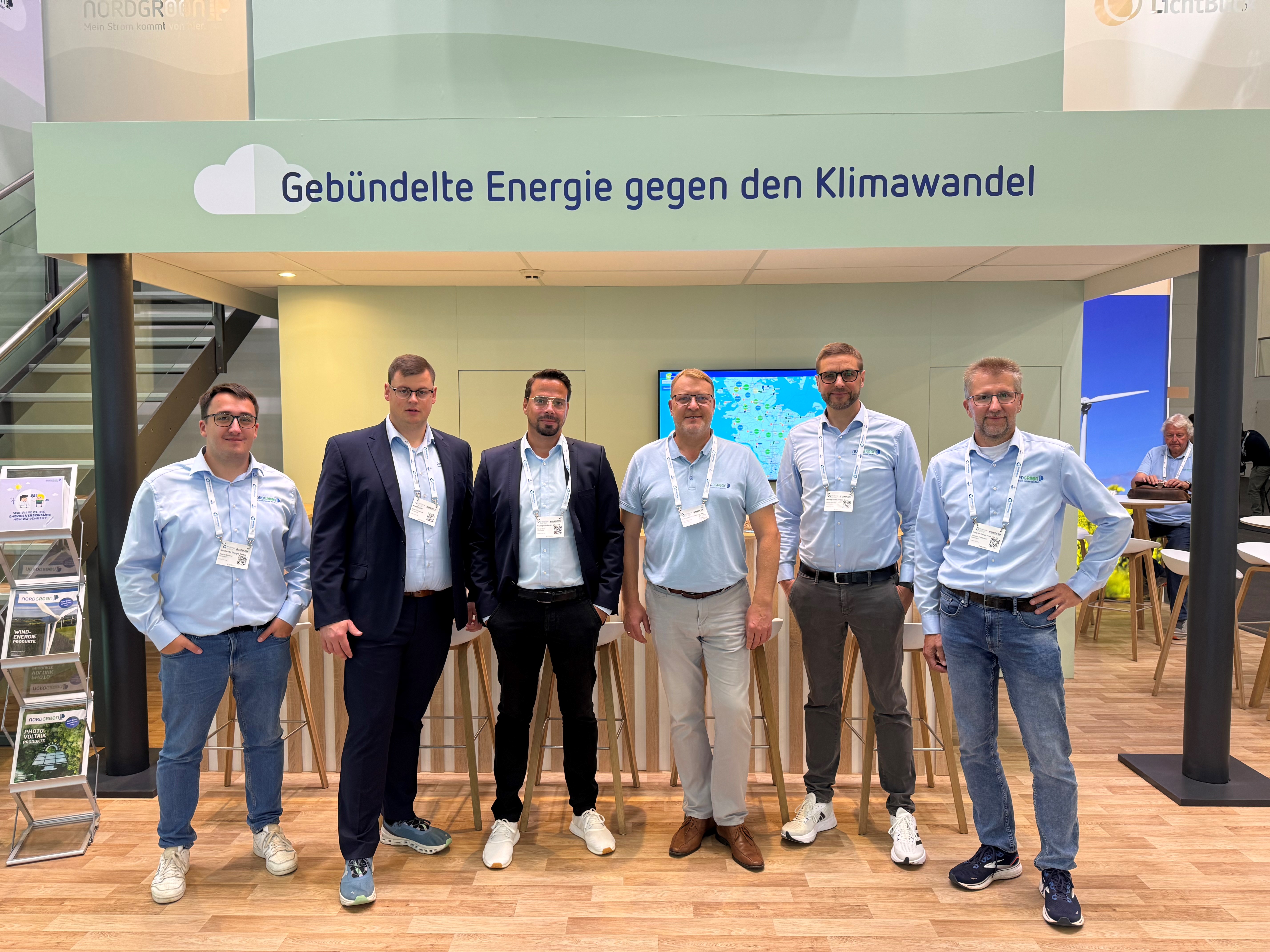 Sechs Männer am Messestand mit dem Schritzug "Gebündelte Energie gegen den Klimawandel"